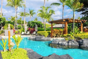 A clear blue pool surrounded by tropical plants and palm trees. - Luxury Sunset Villa | Pool Steps Away | 3 Lanais (Waimea)