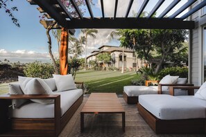 A covered outdoor seating area with a view of a house and lawn. - Luxury Sunset Villa | Pool Steps Away | 3 Lanais (Waimea)