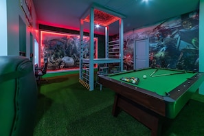 A pool table with a green felt surface, surrounded by a wall with a mural of dinosaurs. - Orlando 5BR Villa w/ Private Pool & Themed Rooms (Clermont)