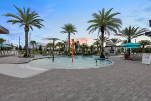 A pool area with palm trees, lounge chairs, and umbrellas. - Modern 5BR Villa w/ Pool 15 min to Disney (Orlando)