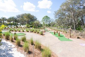 Een golfbaan met zandbunkers, een putting green en een houten hek.