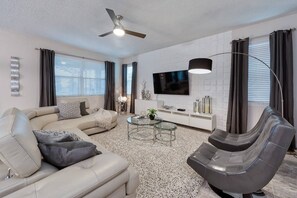 A modern living room with a sofa, armchair, and coffee table. - 5BR Pool Home Solara Resort Near Disney (Kissimmee)