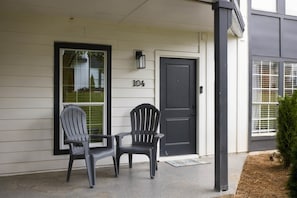 Ein Haus mit einer Veranda, zwei Adirondack-Stühlen, einer Tür mit der Nummer 104 und einer Fußmatte.