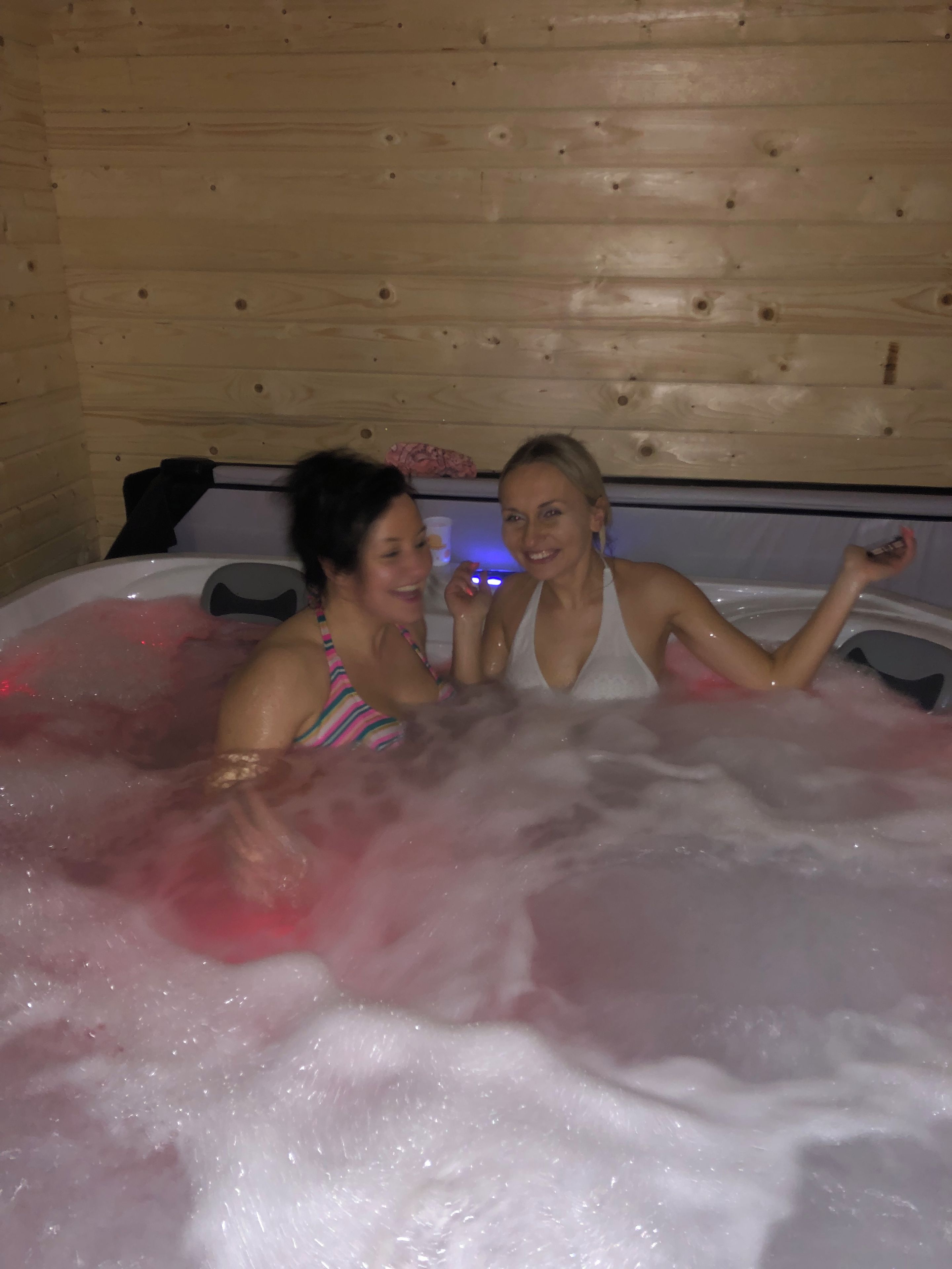 Two people in a hot tub with wooden walls.