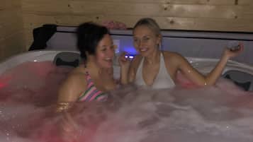 Two people in a hot tub with wooden walls.