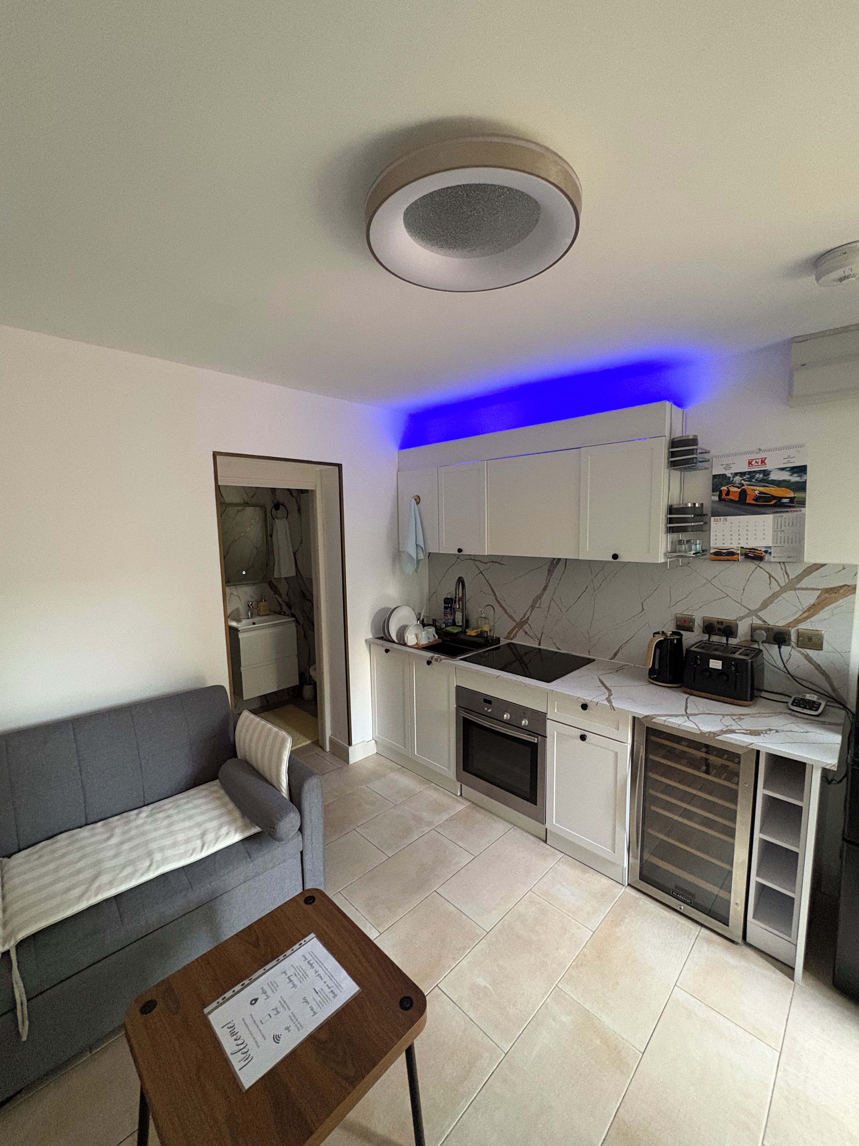 A compact living space with a kitchenette, a sofa, and a small table with a menu.