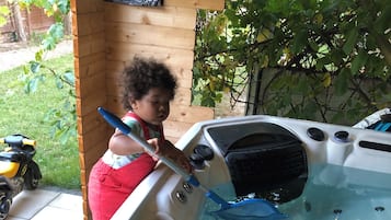 A hot tub with a wooden deck and a child playing with a toy.