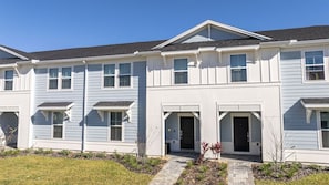 A multi-story residential building with a symmetrical facade, multiple windows, and a central entrance. - 5BR Windsor Cay Pool Home With Game Loft (Clermont)