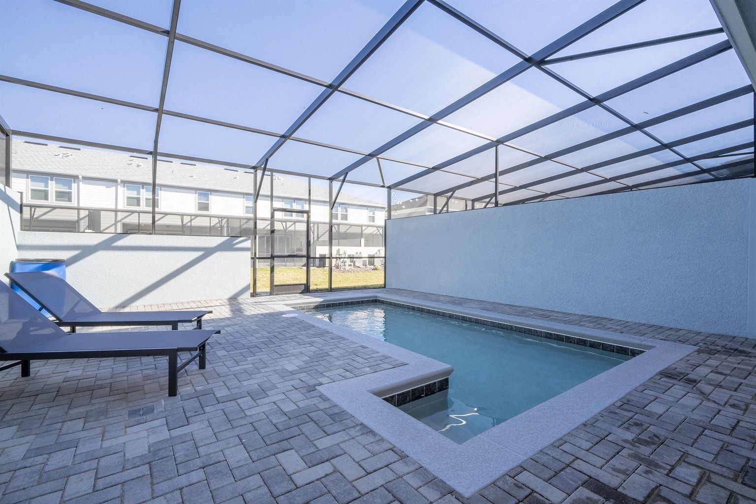 Ein Innenpool mit Glasdecke, Liegestühlen und Fliesenboden.