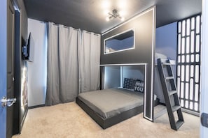 A bunk bed with a ladder, a TV mounted on the wall, and a window with curtains. - 5BR Windsor Cay Pool Home With Game Loft (Clermont)