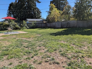 A backyard with a wooden fence, a red umbrella, and a table with chairs. - Cozy 2-bdrm house in Cottage Grove with Fenced Yard, Plenty of Parking (Cottage Grove)