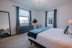 A bedroom with a bed, a dresser, a chair, and a window with curtains. - Storey Lake 5BR Home With Private Pool (Kissimmee)