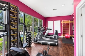 Ein Fitnessstudio mit Cardiogeräten, Krafttrainingsgeräten und einem roten Trainingsball.