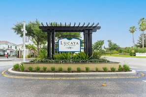 A sign for Lucaya Village with a pergola and plants in front. - Modern 4BR Home in Lucaya Village Kissimmee (Kissimmee)
