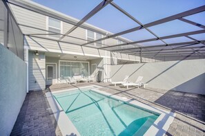 A swimming pool with clear blue water, surrounded by white lounge chairs and a covered patio area. - Modern 5BR Home w/ Pool at Windsor Island (Davenport)