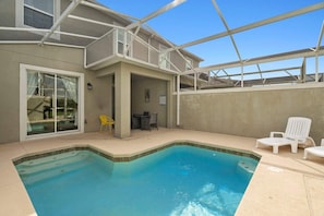 A swimming pool with a covered patio area, a dining table, and outdoor chairs. - 4BR Townhome w/ Pool at Champions Gate (Davenport)
