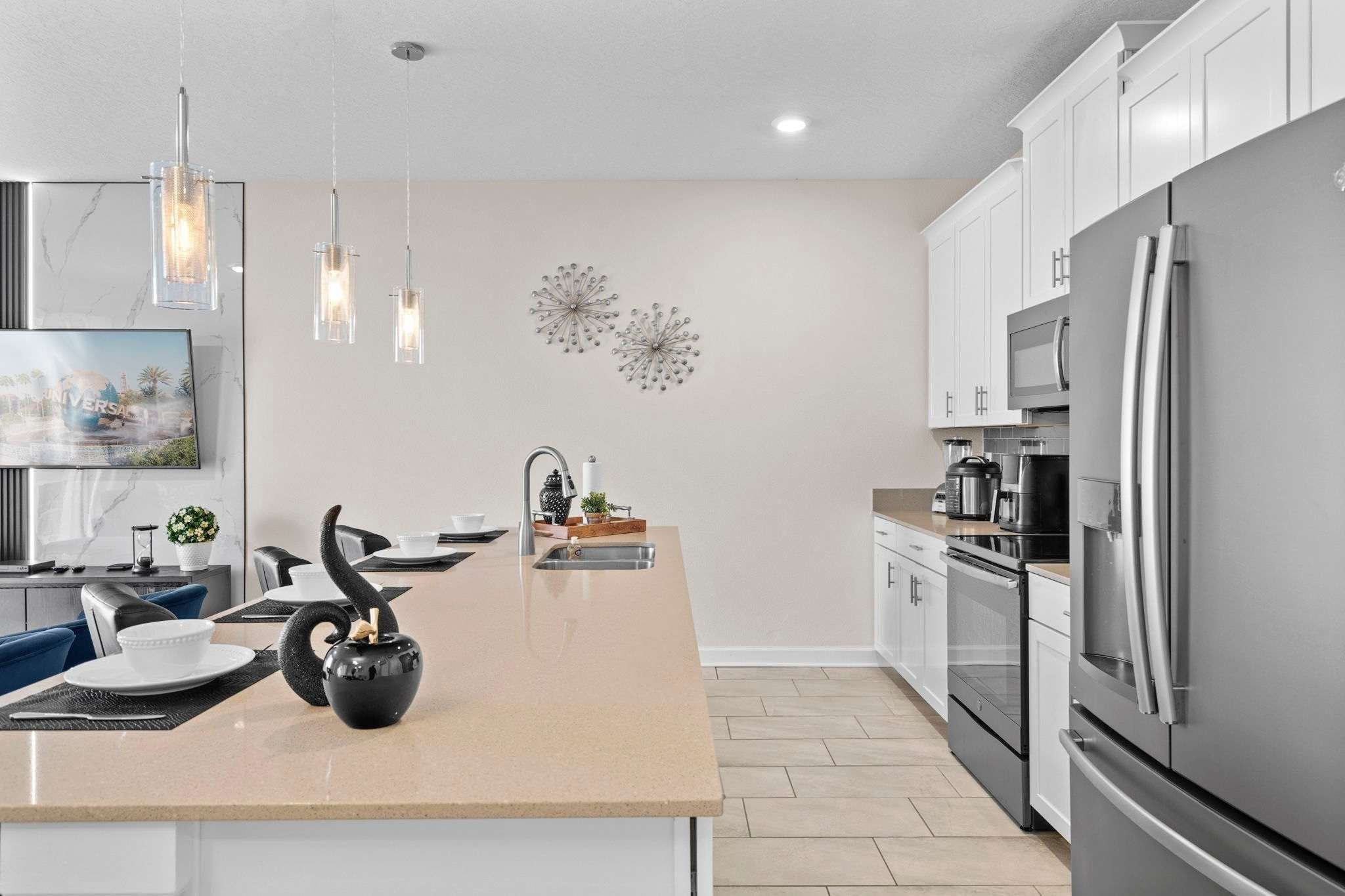 A modern kitchen with a central island, stainless steel appliances, pendant lighting, and a decorative wall piece.