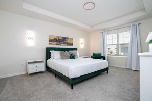 Een slaapkamer met een bed, nachtkastjes, gordijnen voor het raam en een schilderij aan de muur.
