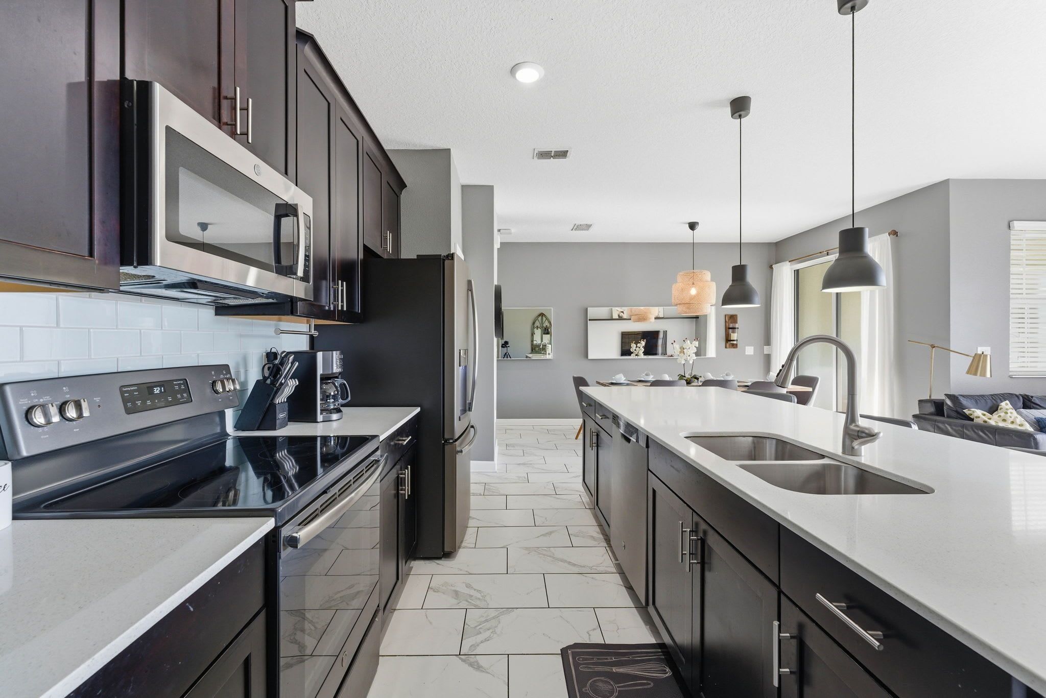 A modern kitchen with dark cabinets, a stainless steel range, and a large island with a sink.