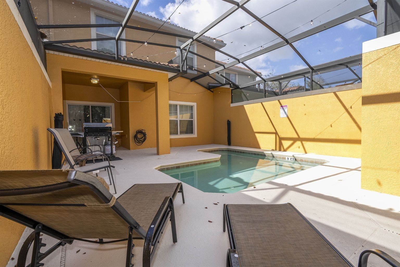 A rooftop pool area with a glass ceiling, outdoor seating, and a barbecue setup.