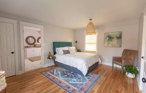 A bedroom with a bed, a chair, a rug, a window with blinds, and a painting on the wall. - Cozy 3 bedroom home in historic Cleveland walking distance from Lee University (Cleveland)