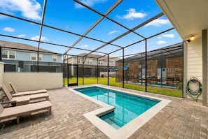 A covered outdoor swimming pool with lounge chairs, a brick patio, and a view of neighboring houses. - 5BR Themed Home w/ Pool Windsor Island (Davenport)