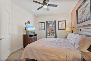 A bedroom with a bed, a ceiling fan, a dresser, a TV, and framed pictures on the wall. - 4BR Home Near Disney With Clubhouse (Kissimmee)