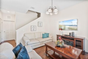 A living room with a sofa, coffee table, and artwork on the wall. - 4BR Home Near Disney With Clubhouse (Kissimmee)