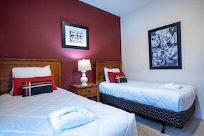 Ein Hotelzimmer mit zwei Betten, einem Nachttisch, einer Lampe und zwei gerahmten Bildern an der Wand.