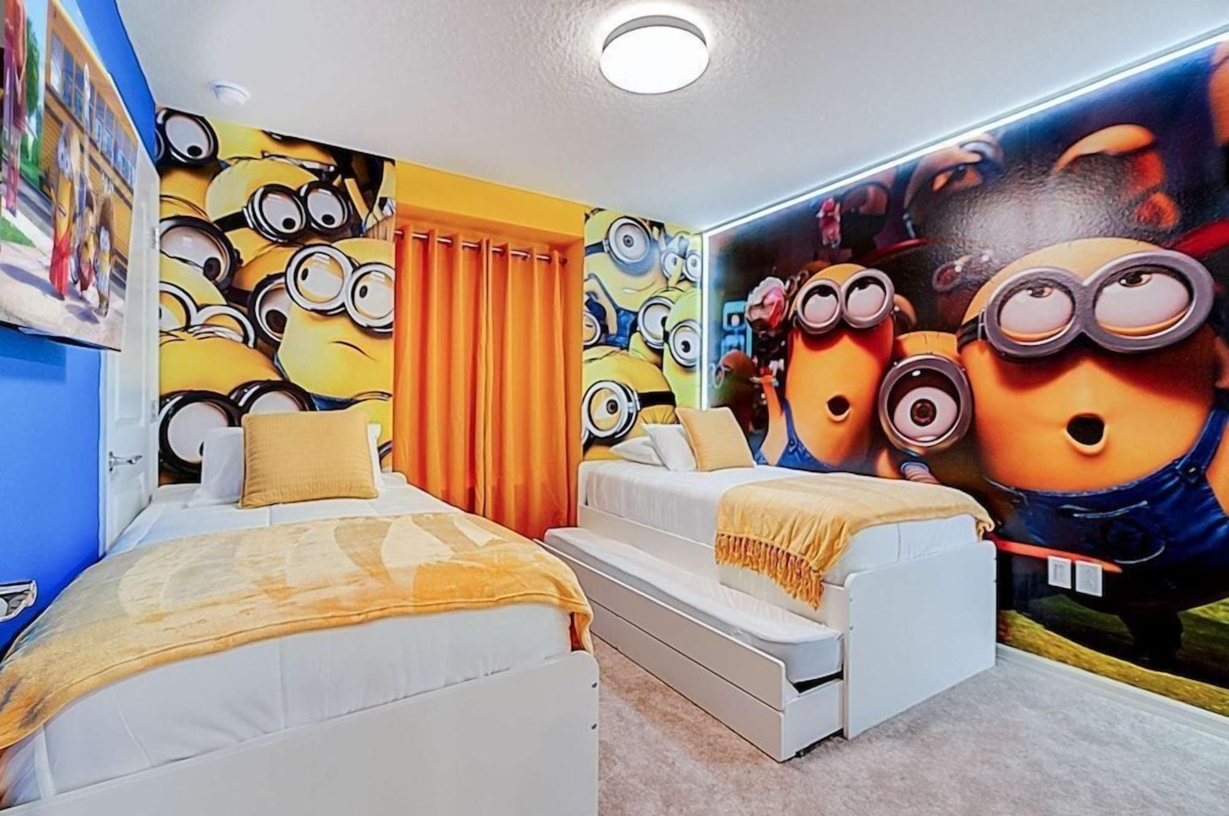 A bedroom with two beds, a mural of minions, and a window with curtains.