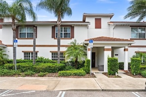A multi-story building with a covered entrance and a wheelchair-accessible sign. - 4-bedroom House at Storey Lake With Private Pool (Kissimmee)