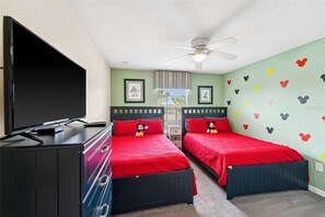 A bedroom with two beds, a TV, and Mickey Mouse-themed wall decals. - 4-bedroom House at Storey Lake With Private Pool (Kissimmee)