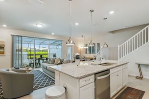 A modern kitchen with a large island, white cabinetry, and pendant lighting. - 5BR Solterra Townhome, Private Pool (Davenport)