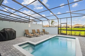 Une piscine intérieure offrant une vue dégagée sur le paysage environnant, un espace détente couvert avec des chaises et un barbecue.