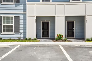 A modern building with two doors, a parking lot, and a small garden area. - 5BR Solterra Townhome, Private Pool (Davenport)