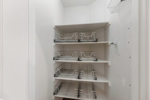 Ein heller Innenraum mit vier Regalen aus Draht vor einer Wand.