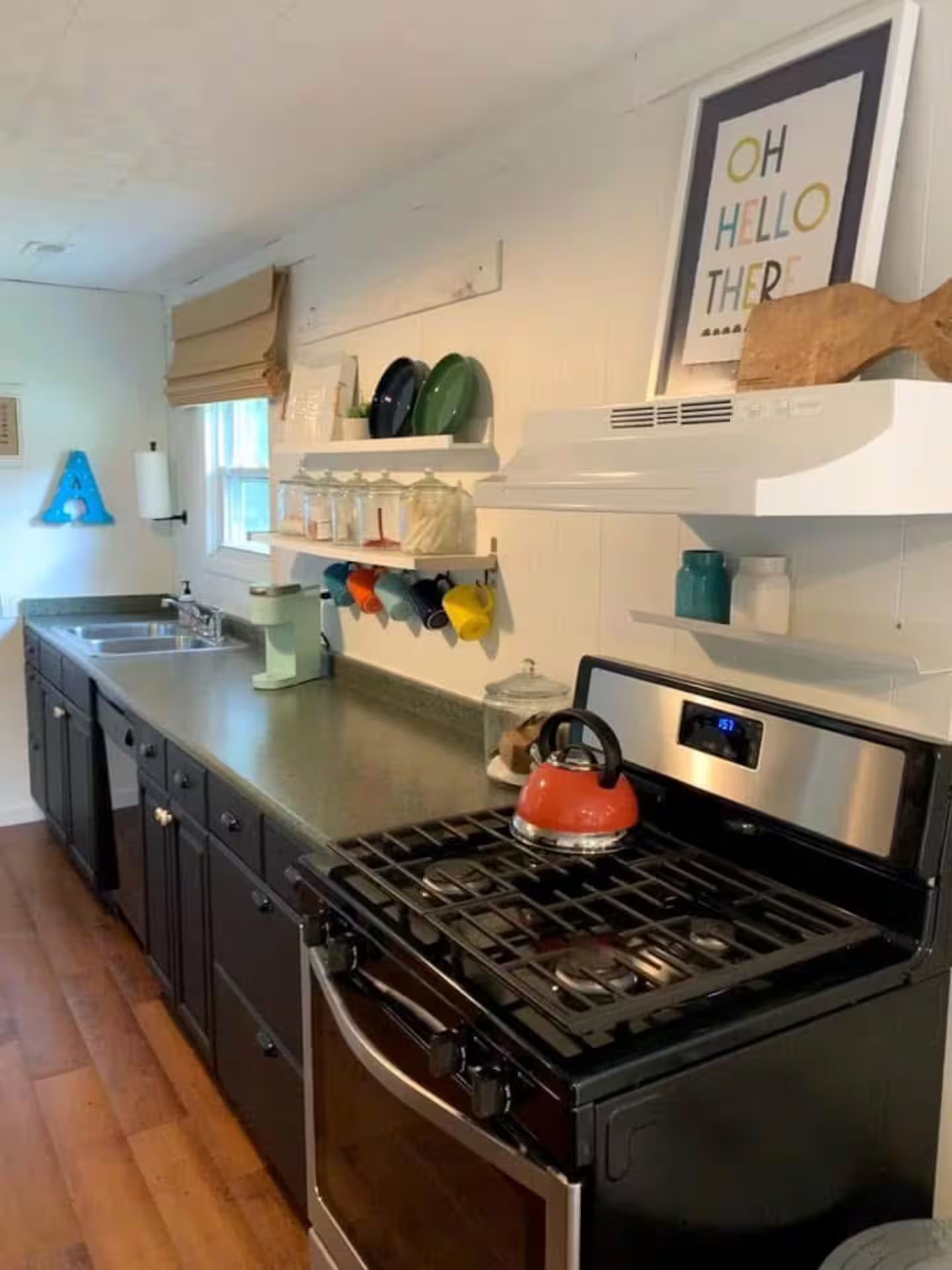 A kitchen with a stove, cabinets, and a window.