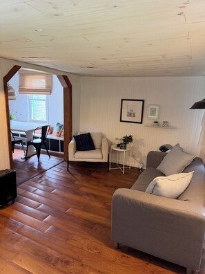 Una sala de estar con sofá, sillón y comedor con sillas y una mesa.