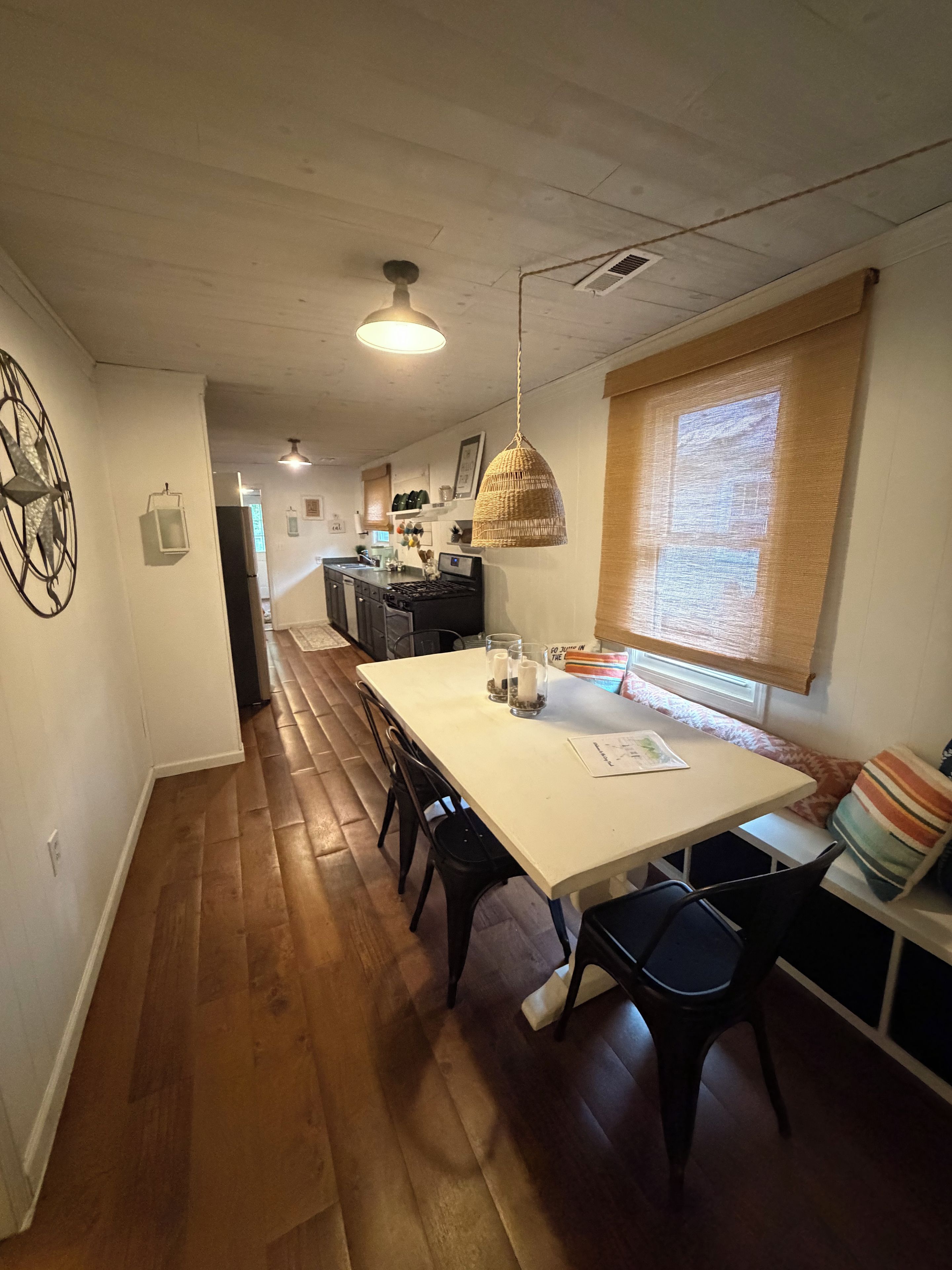 A dining area with a long table, chairs, and a hanging light fixture.