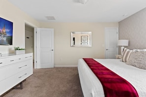 A bedroom with a bed, a dresser, a mirror, and a door. - 5BR Home w/ Private Pool - Storey Lake Resort (Kissimmee)