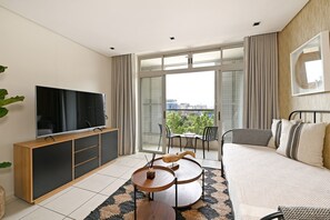 A modern living room with a flat-screen TV, a sofa, a coffee table, and a balcony with a view of the city. - Secure One Bed Apartment Modern and Spacious (Cape Town)