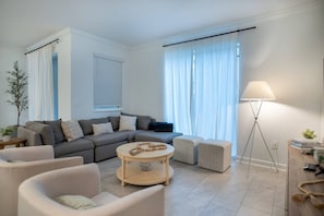 A modern living room with a grey sofa, a round coffee table, and a floor lamp. - Disney Area 4BR Home w/ Pool & Themed Rooms (Davenport)