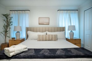 A neatly arranged bedroom with a bed, two bedside tables, a lamp on each, a framed picture on the wall, and a potted plant. - Disney Area 4BR Home w/ Pool & Themed Rooms (Davenport)