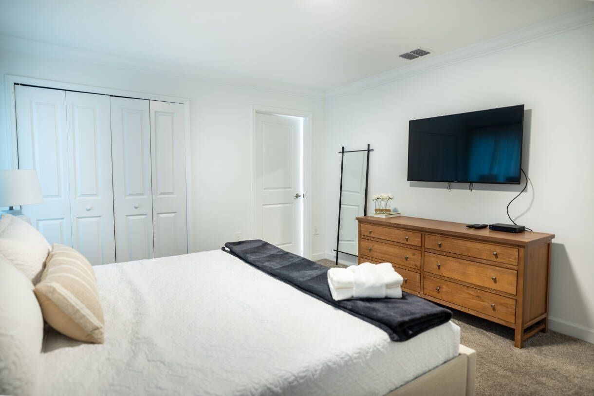 A bedroom with a bed, a dresser, a television, and a closet.