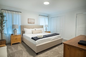 Une chambre à coucher avec un lit, des tables de chevet, une lampe, une plante et un bureau en bois.