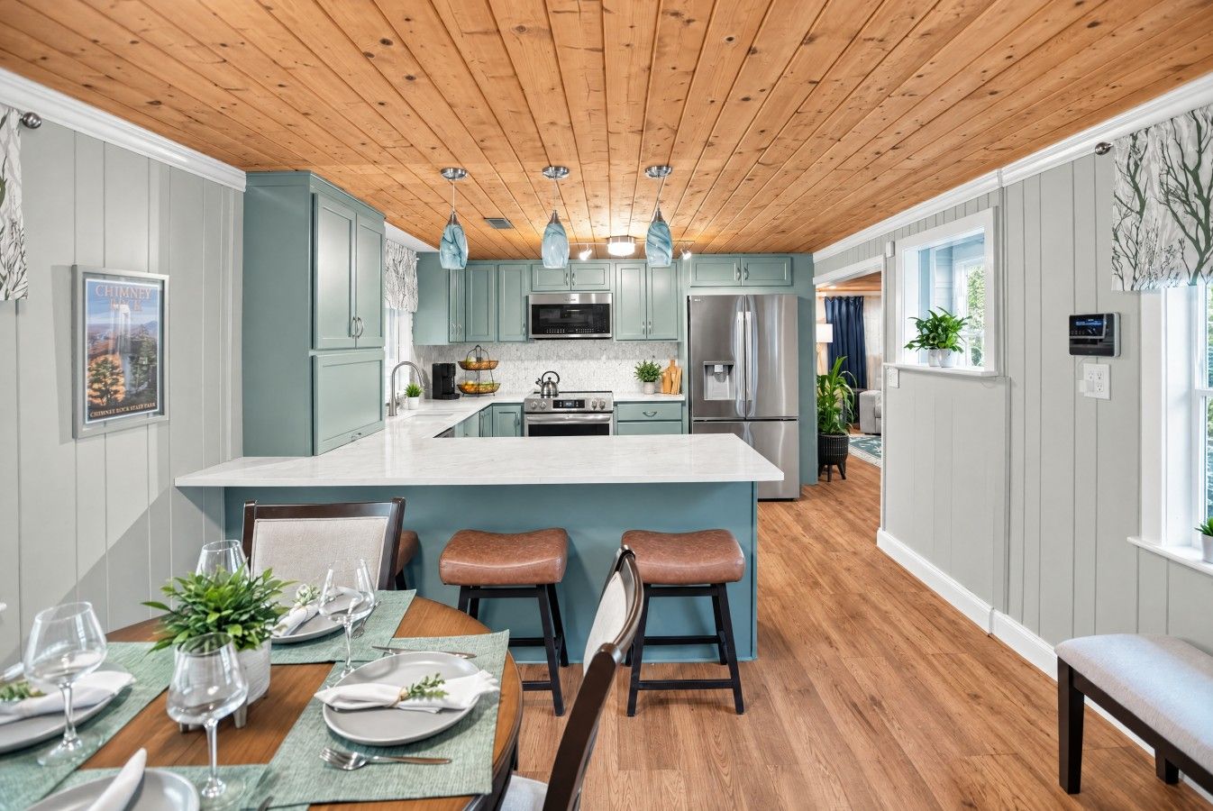 A modern kitchen with a central island, wooden ceiling, and light blue cabinetry.