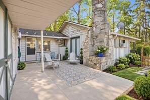 A residential property with a covered patio, outdoor seating, and a stone pillar. - Cozy Royal Pines Cottage w Courtyard & Patio (Royal Pines)