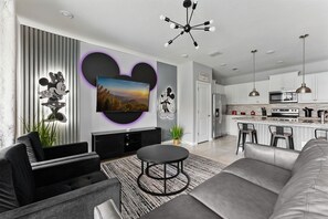 Ein modernes Wohnzimmer mit Flachbildfernseher, rundem Couchtisch und einer Couch.