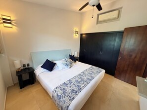 Een slaapkamer met een bed, nachtkastjes, een kledingkast en een plafondventilator.