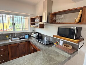 Een moderne keuken met een ingebouwde magnetron, een koffiezetapparaat en een spoelbak.